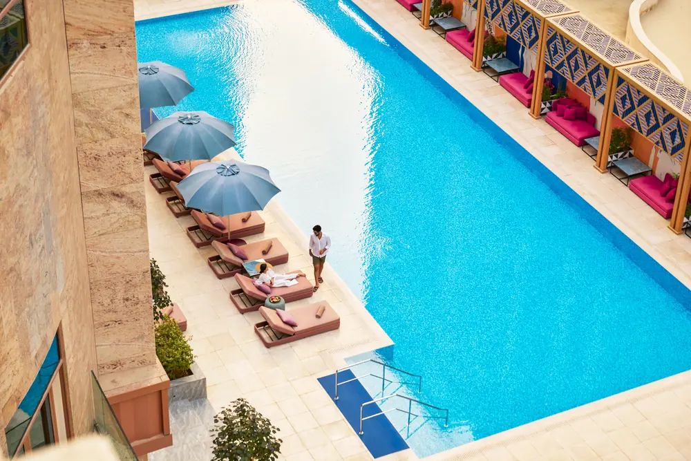 The pool terrace at Andaz Doha from above, loungers and parasols along one edge