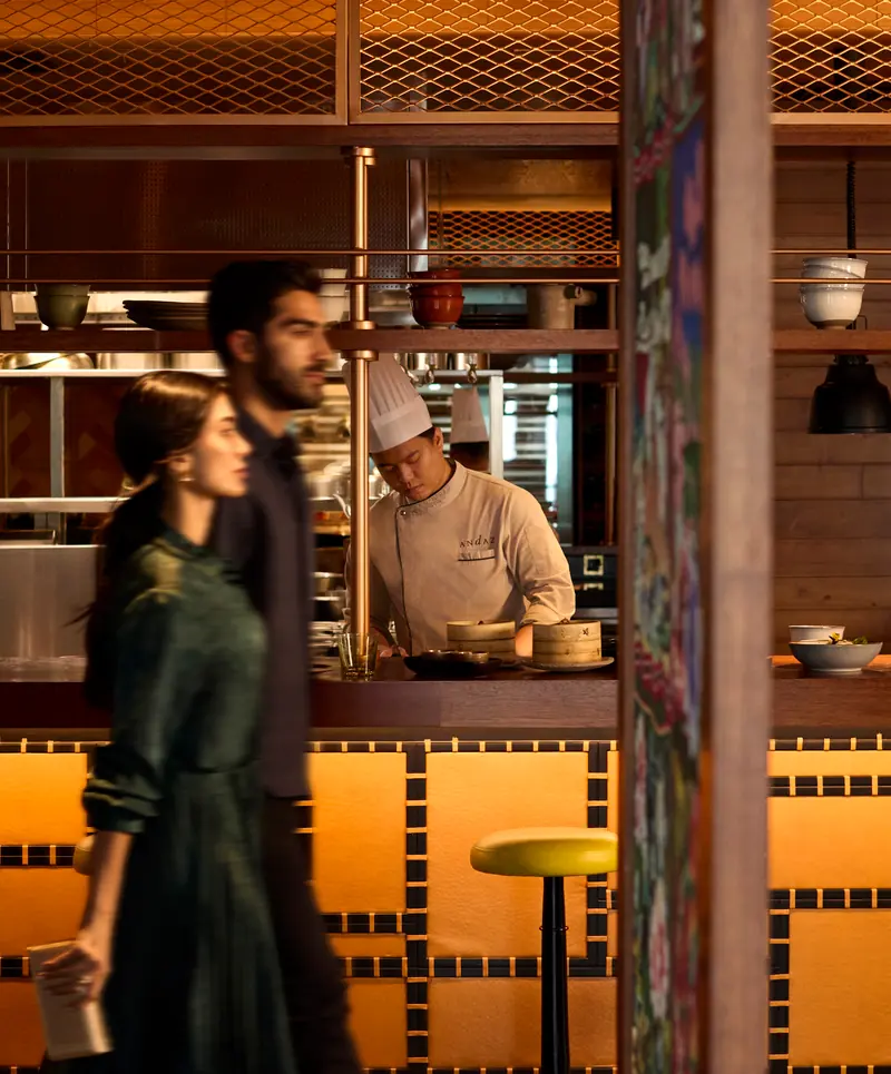 Guests passing the open kitchen at the Andaz Doha restaurant