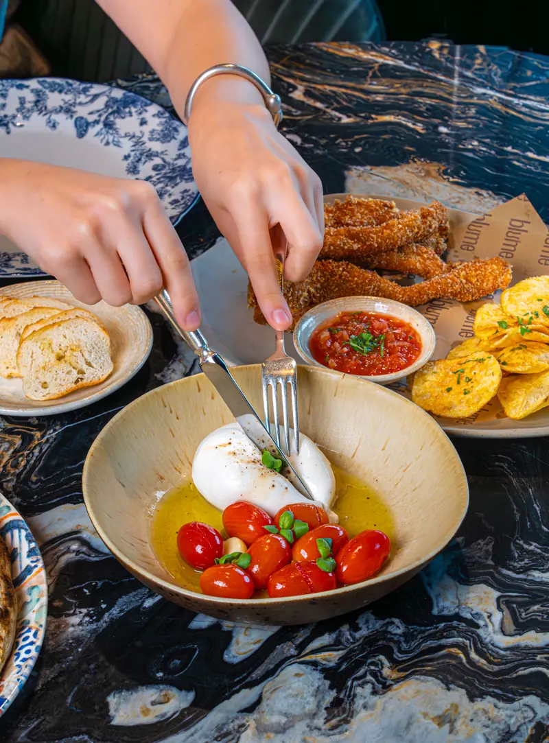 Burrata, tomatoes and bread on the marble table at Blume Dubai Mall