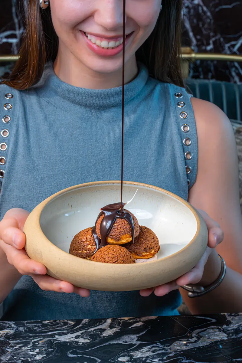 Chocolate poured over profiteroles at Blume Dubai Mall