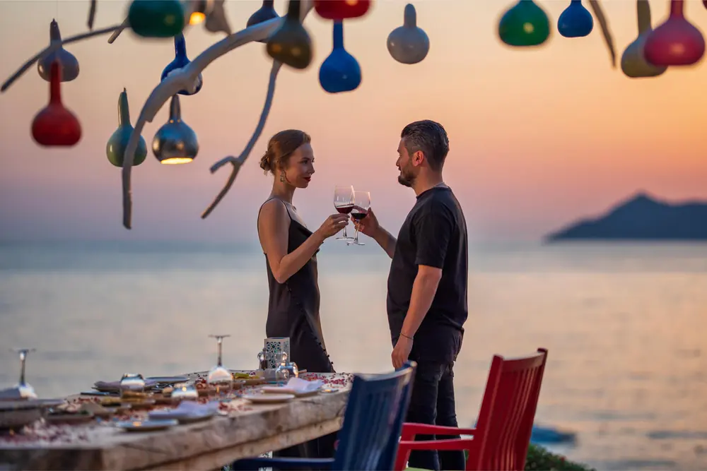 Two guests raising a toast at the terrace table at Liberty Lykia at sunset
