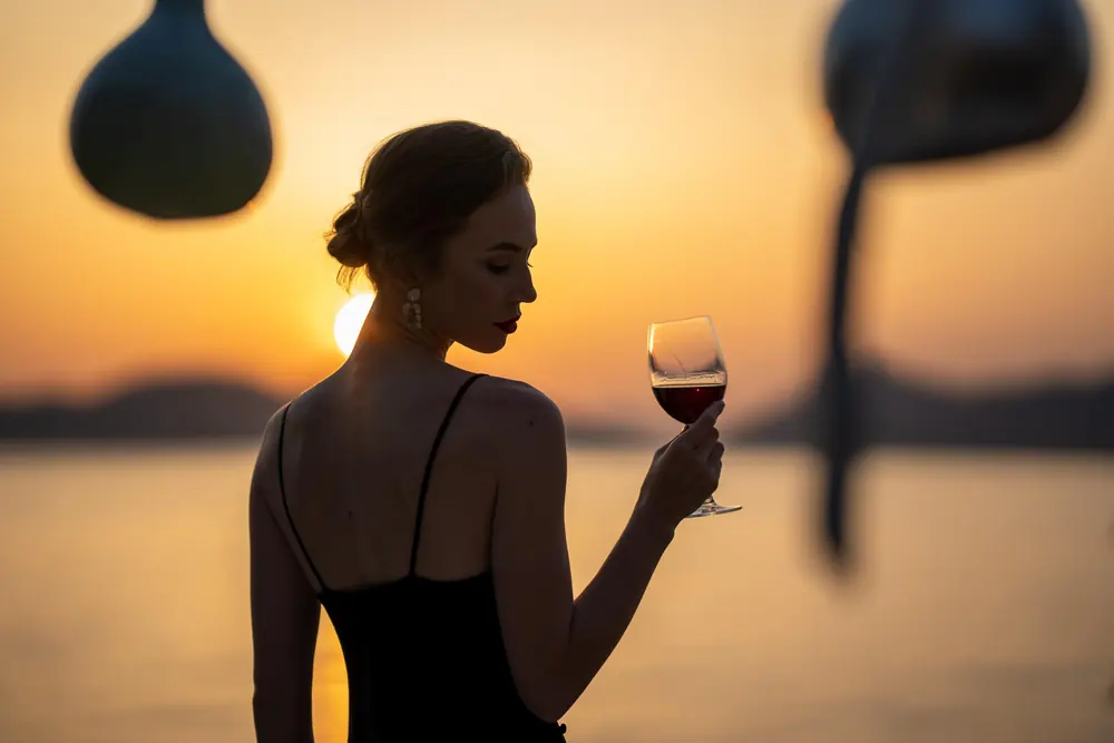 A guest with a glass of wine against the sunset at Liberty Lykia