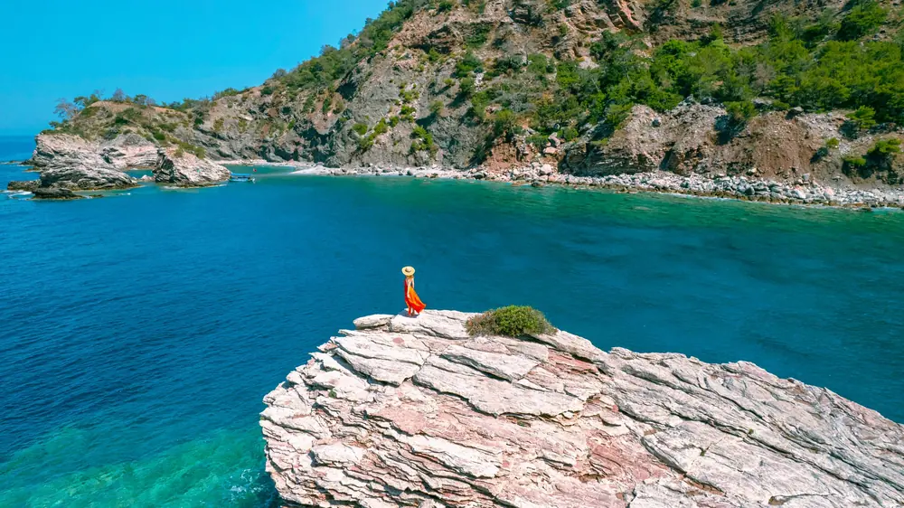 A guest standing on the rock shelf above the turquoise bay below Liberty Lykia