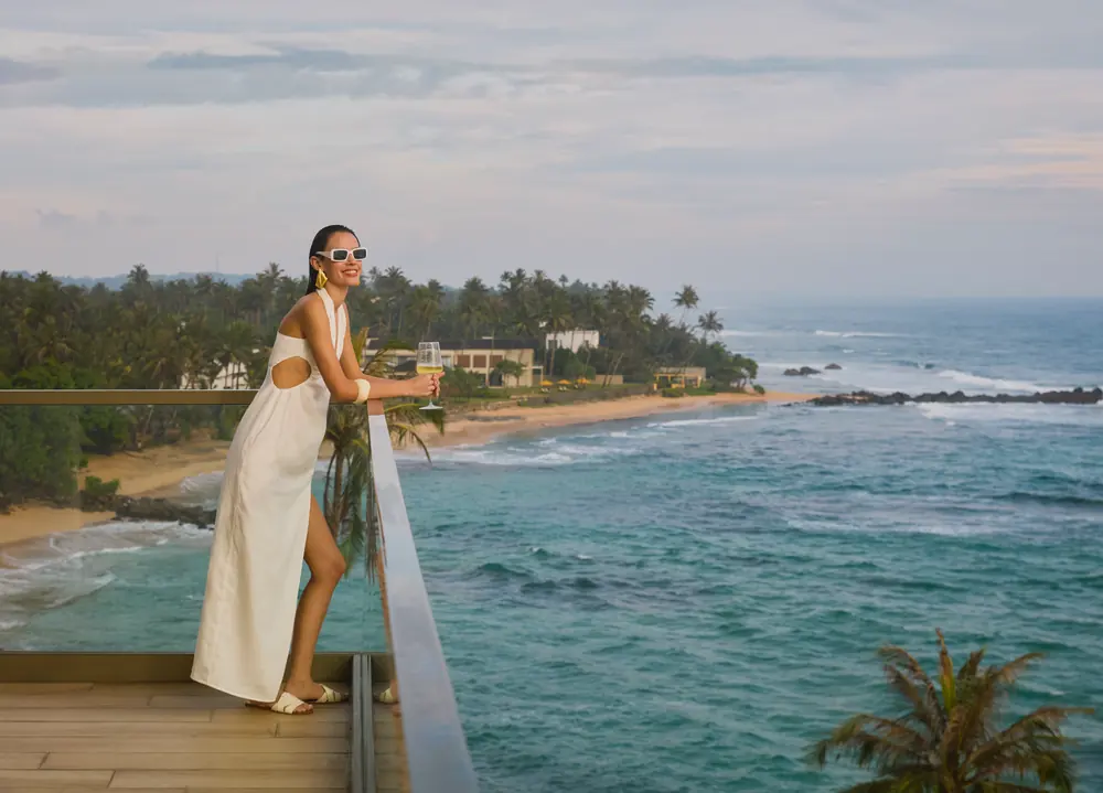 A guest on the balcony above the coastline at Radisson Collection Galle