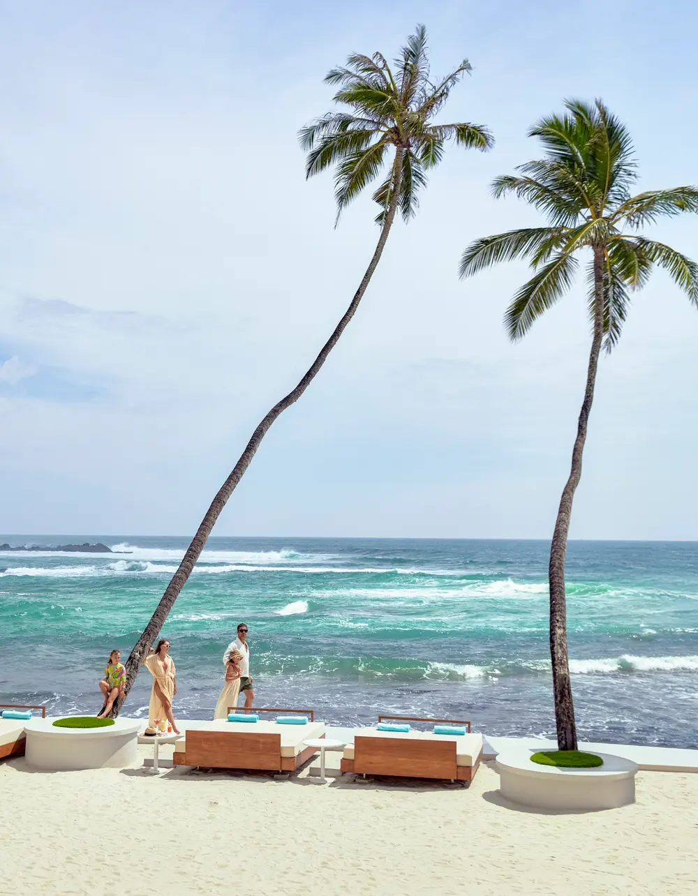 Daybeds on the sand beneath tall leaning palms at Radisson Collection Galle