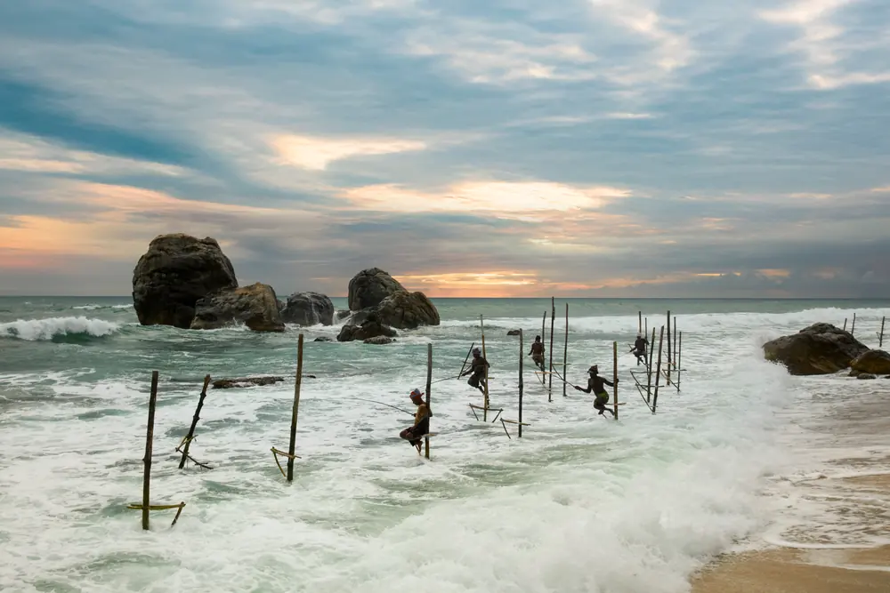 Traditional stilt fishermen in the surf on the coast at Galle, Sri Lanka